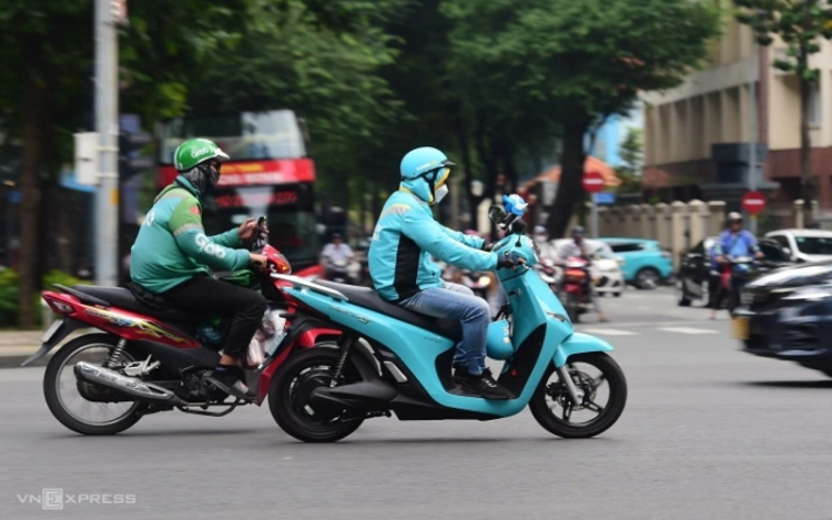 TP HCM sẽ làm gì để chuyển 400.000 xe xăng sang xe điện?. Tài xế hai hãng xe sử dụng xe xăng và xe điện chạy trên đường trung tâm TP HCM. Ảnh: Thanh Tùng